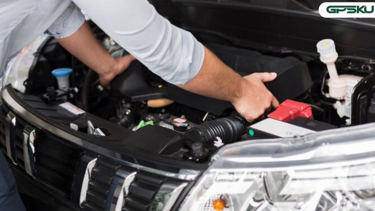 Mekanik sedang memeriksa jaringan kabel-kabel kelistrikan mobil di bawah kap mesin.