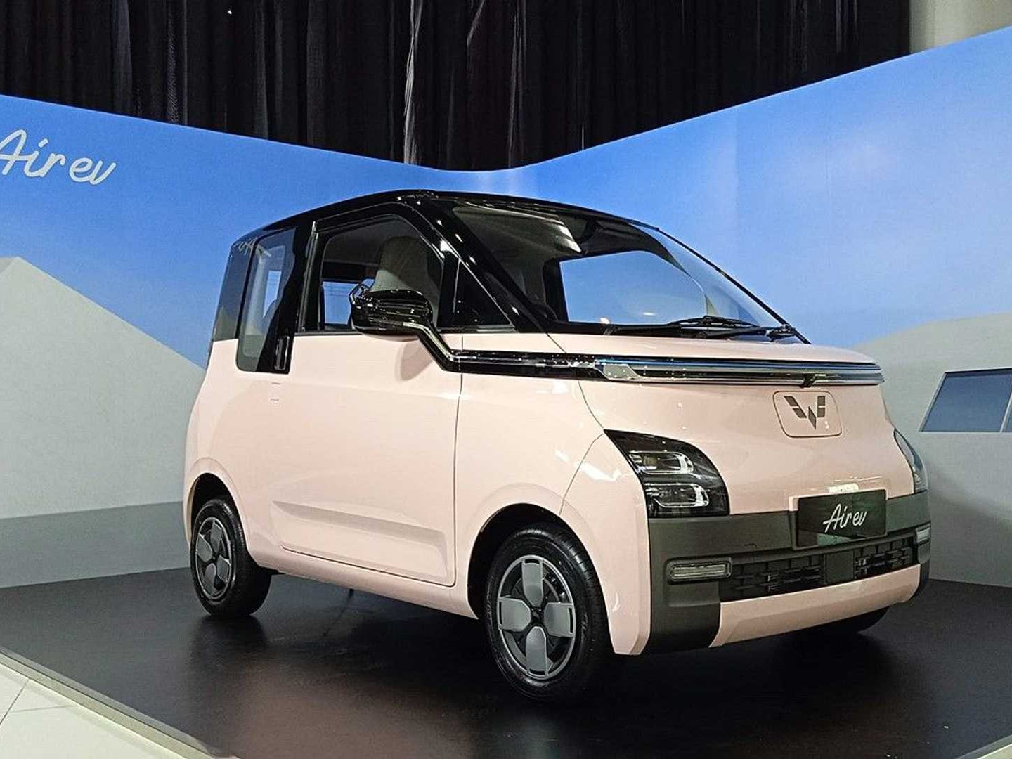 Gambar Wuling Air EV diparkir di stasiun pengisian daya EV atau tempat perkotaan modern di Kelapa Gading, Jakarta Utara, menonjolkan desain unik dan sifat ramah lingkungannya.