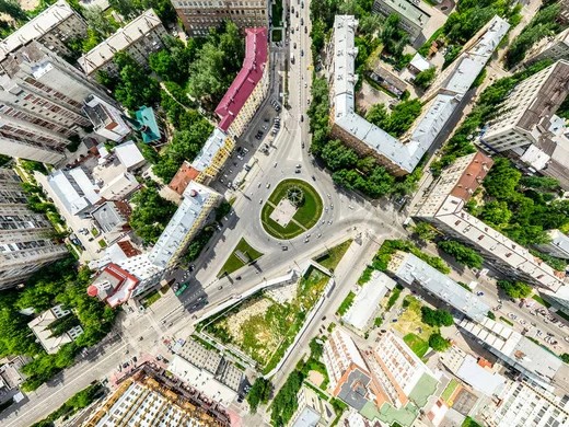 Gambar gedung apartemen modern dengan pemandangan persimpangan kota yang ramai.