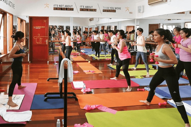 Orang-orang sedang mengikuti kelas yoga atau cycling di studio gym butik yang stylish dan modern.