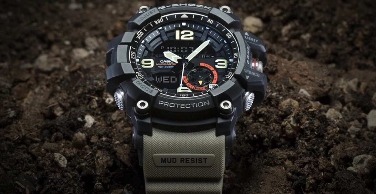 Jam tangan outdoor multifungsi di pergelangan tangan, dengan latar belakang peta dan kompas.