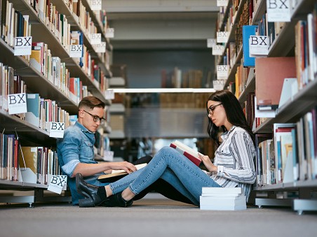 Gambar interior perpustakaan universitas dengan mahasiswa belajar.