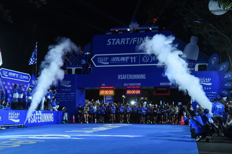 Pelari di Bandung Marathon melewati Gedung Sate dengan latar belakang kerumunan penonton.
