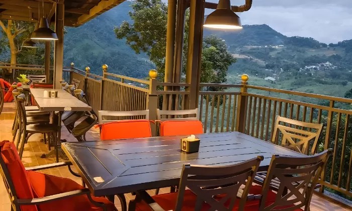 Pasangan menikmati makan malam romantis di teras villa dengan pemandangan kota yang berkelap-kelip di malam hari di Bogor.