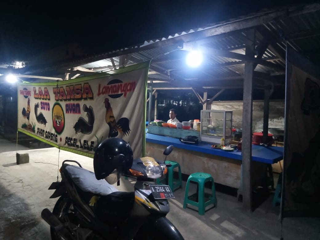 Suasana warung pecel lele di malam hari dengan cahaya lampu gantung.