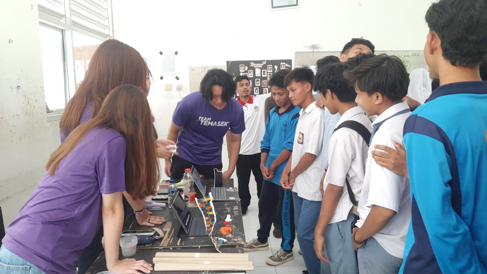 Gambar siswa-siswi berkolaborasi dalam kelompok, mempresentasikan proyek di depan kelas.