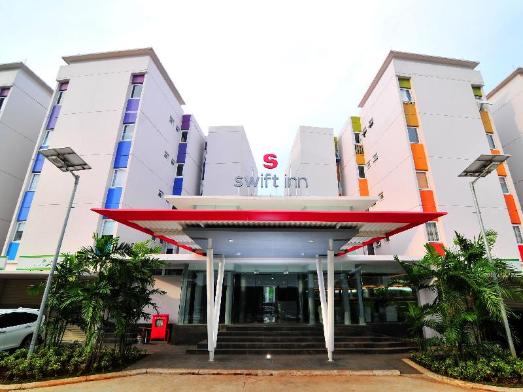 Gambar eksterior hotel dengan taksi atau shuttle bandara di depannya.