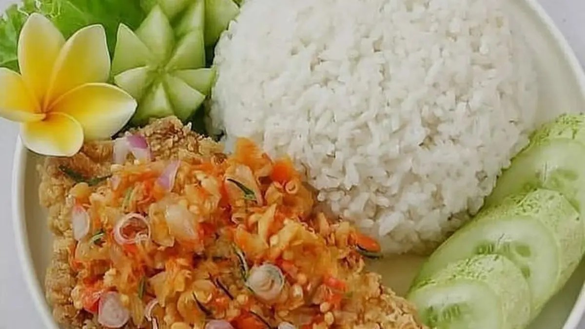 Sepiring ayam geprek sambal matah dengan nasi hangat dan lalapan di meja.