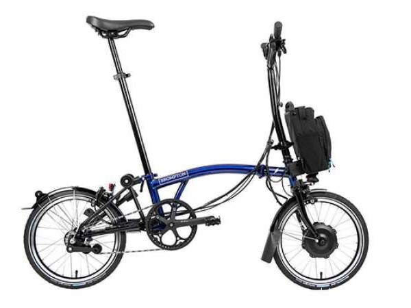 Gambar sepeda Brompton Bicycle terlipat berdiri dengan elegan di lobi kantor modern atau kafe, menonjolkan daya tarik perkotaan yang canggih, dengan latar belakang samar SCBD Jakarta Pusat.