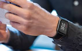 Smartwatch di pergelangan tangan, menampilkan notifikasi dan grafik detak jantung.