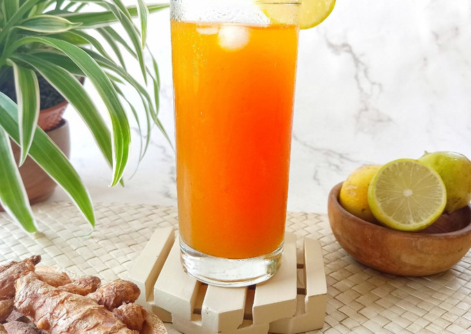 Segelas minuman kunyit asam dingin dengan es dan irisan lemon.