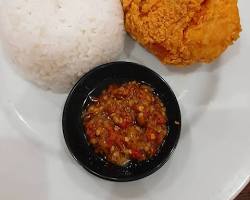 Potongan ayam goreng krispi dengan kulit renyah di atas piring, disajikan dengan sambal.