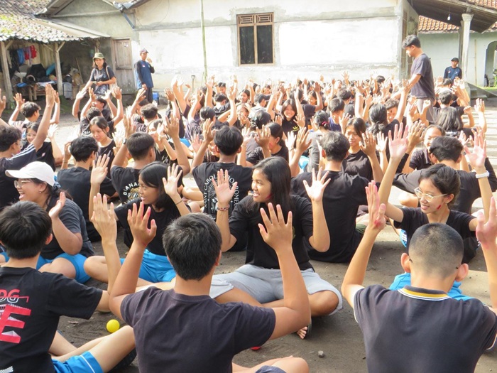 Gambar siswa-siswi berinteraksi dengan warga lokal atau anak-anak di sebuah program komunitas.