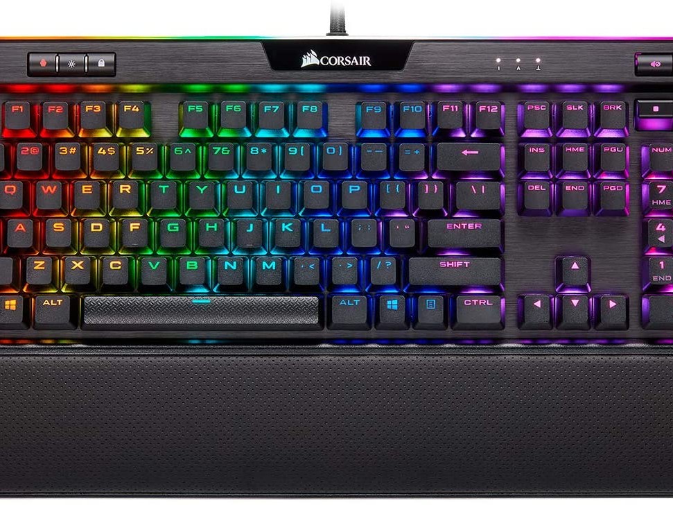 Gambar keyboard Corsair K95 RGB Platinum XT di atas meja, dengan periferal Corsair lainnya (mouse, headset) juga terlihat dan pencahayaan RGB-nya disinkronkan dengan sempurna, menekankan ekosistem yan