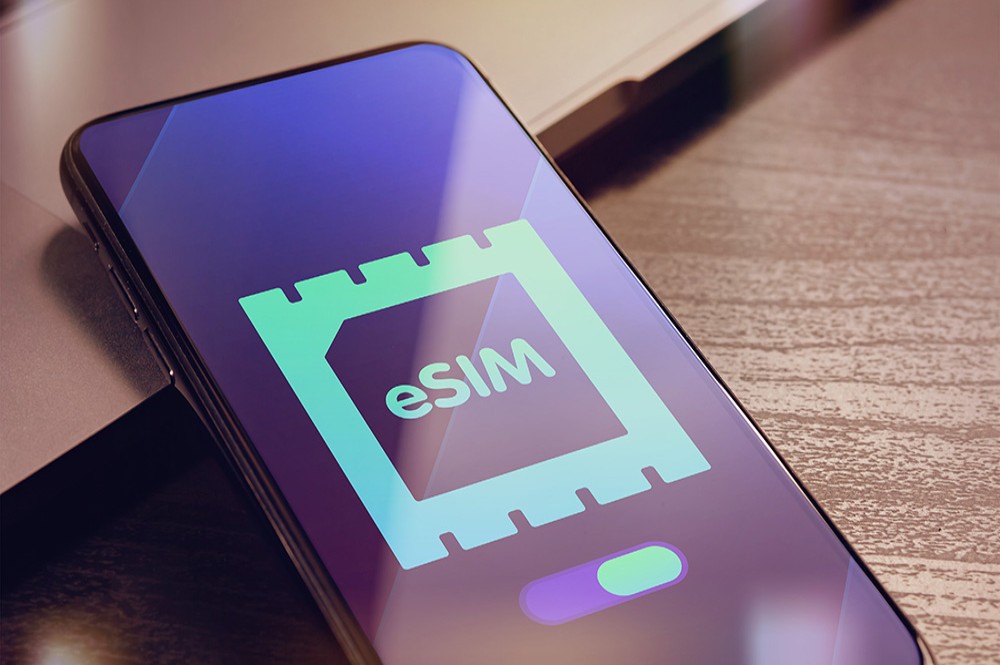 Layar ponsel menampilkan ikon eSIM, dengan gambar kartu SIM fisik yang transparan di latar belakang, menggambarkan konsep eSIM.
