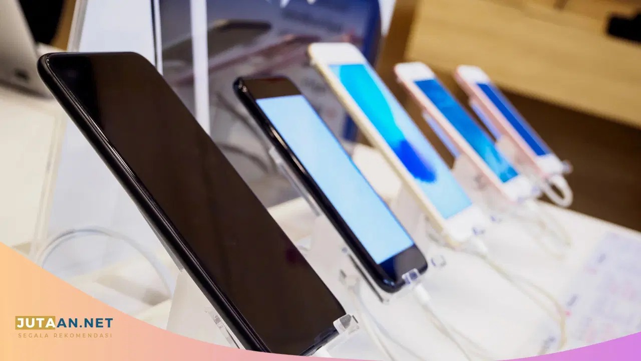 Tangan memilih handphone bekas di display toko gadget bekas.