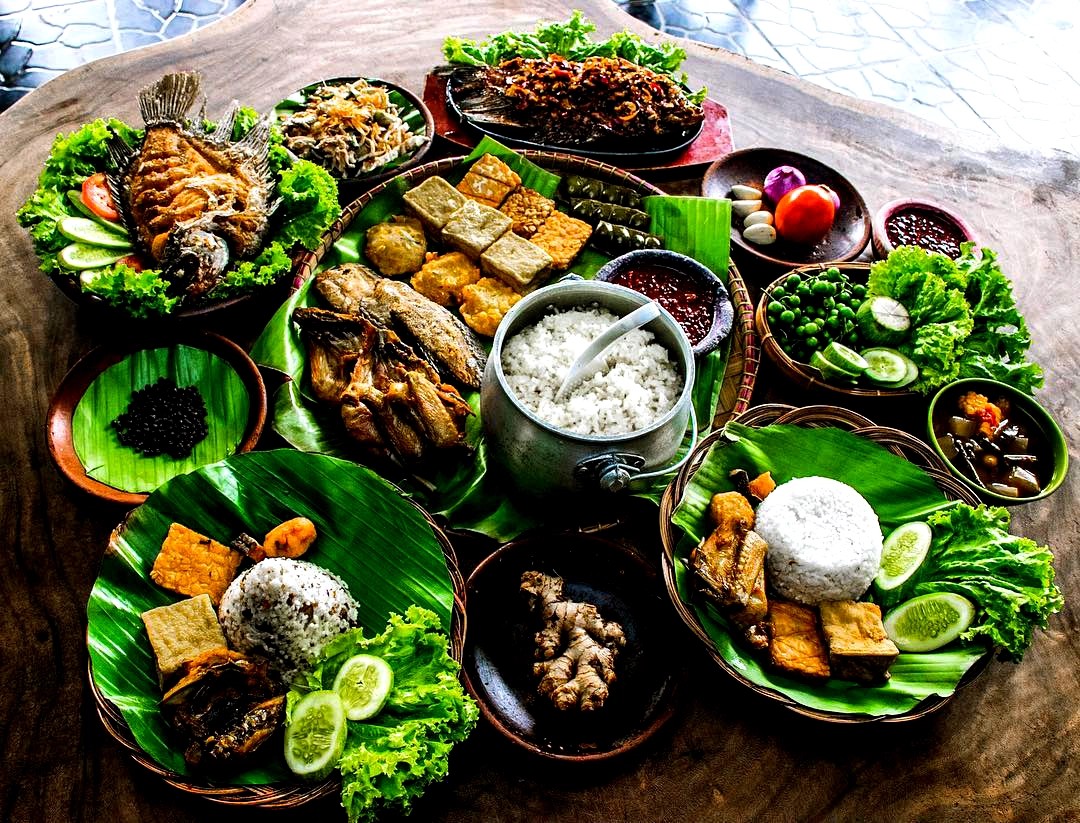 Keluarga menikmati nasi liwet komplit di saung makan dengan pemandangan hijau.