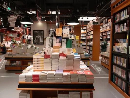 Gambar interior toko buku diskon dengan banyak buku dan tanda penjualan.