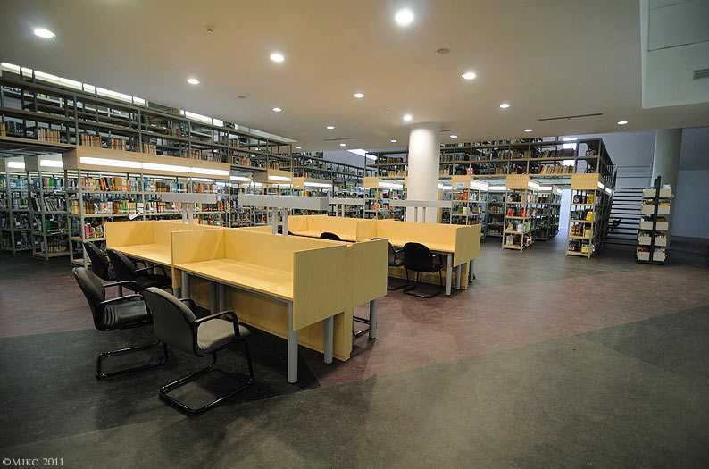 Gambar interior perpustakaan universitas modern dengan banyak mahasiswa.