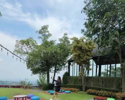 Nasi timbel disajikan di gazebo kayu dengan latar belakang pemandangan perbukitan hijau.