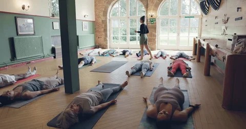 Sekelompok orang melakukan posisi yoga di studio yang tenang dengan pencahayaan lembut.