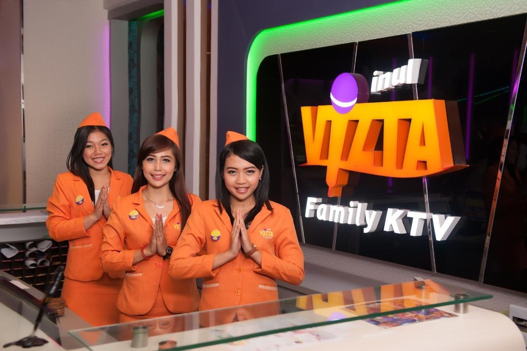 Keluarga sedang bernyanyi bersama di ruangan karaoke Happy Puppy atau Inul Vizta dengan suasana ceria.