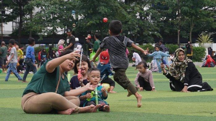 Keluarga sedang piknik di area rumput sintetis Alun-Alun Bandung.