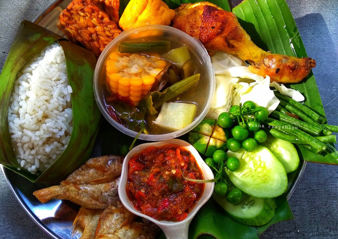 Aneka masakan Sunda halal disajikan di meja makan dengan nasi timbel dan lalapan.