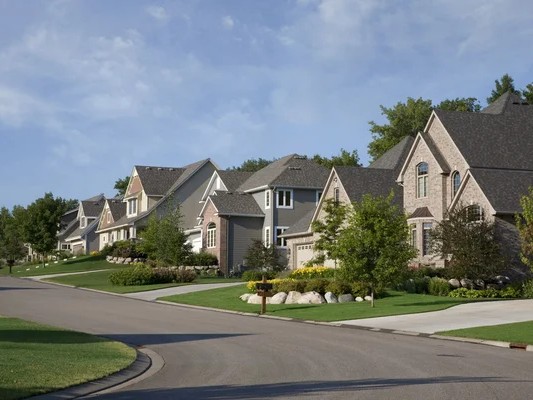 Gambar jalanan perumahan suburban yang tenang dengan halaman hijau.
