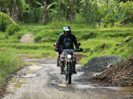 Gambar Kawasaki KLX150 di jalan tanah dengan latar belakang alam (misalnya, bukit atau hutan) di dekat Setiabudi, Bandung, menonjolkan kemampuan dual-sport dan kesiapan berpetualangnya.