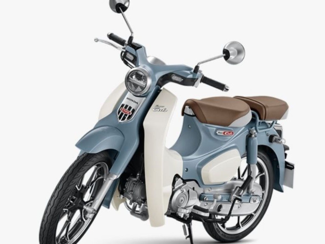 Gambar Honda Super Cub C125 diparkir dengan gaya di jalan bersejarah atau pemandangan indah di Dago, Bandung, menonjolkan desain retro dan daya tarik premiumnya.