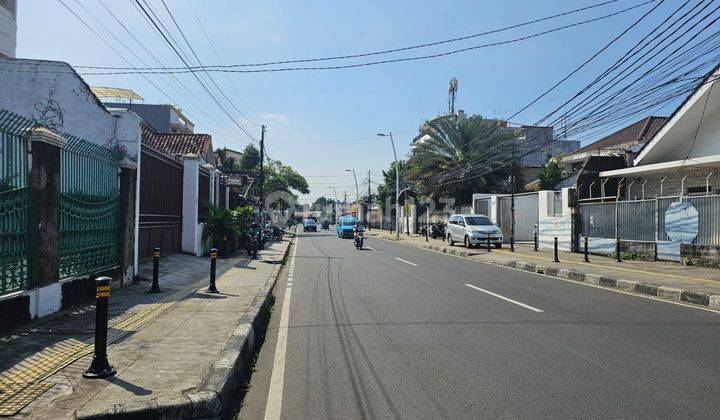 Gambar jalanan yang ramai di Jatinegara dengan bangunan perumahan dan komersial.