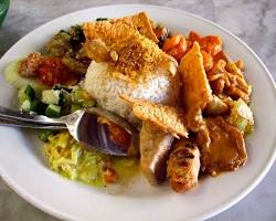 Nasi campur dengan berbagai lauk khas Indonesia seperti rendang dan sayuran.