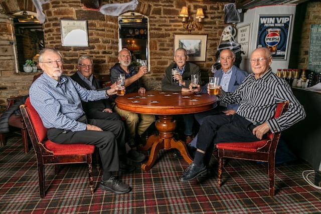 Sekelompok teman sedang bersantai di bar setelah jam kantor dengan minuman dan obrolan.