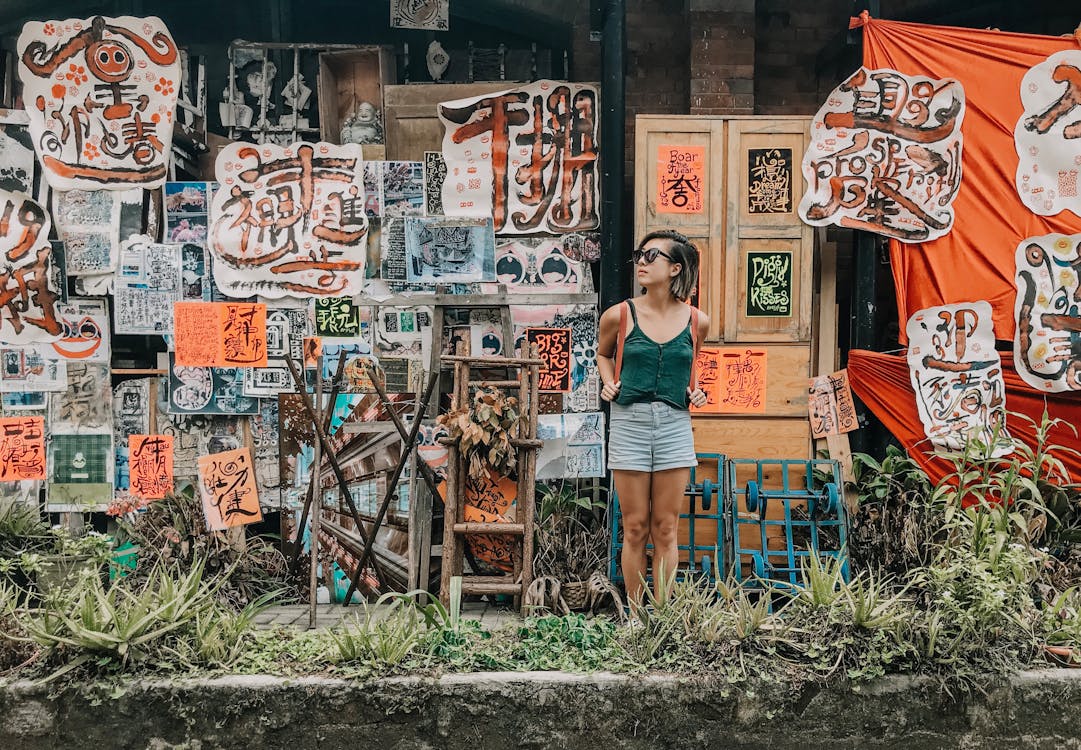 Perempuan muda sedang berpose di depan mural dinding yang estetik di sebuah cafe.