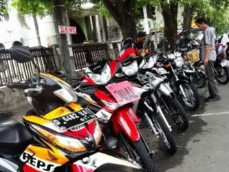 Gambar pasar motor bekas (bursa motor) outdoor yang ramai dengan banyak motor dipajang dan pembeli berjalan-jalan.