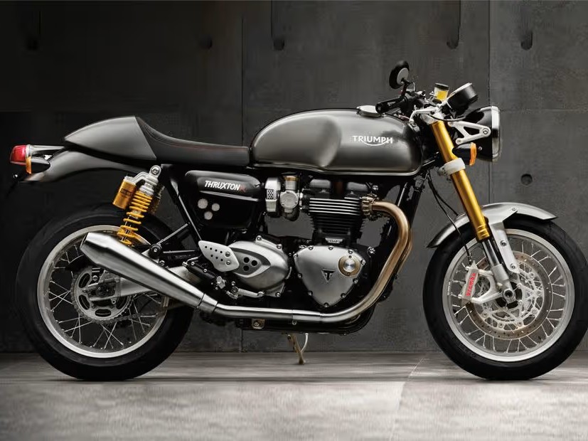 Gambar Triumph Bonneville T120 atau Thruxton RS diparkir dengan elegan di jalan yang teduh atau di depan bangunan mewah di Pondok Indah, menonjolkan desain klasik dan daya tarik premiumnya.