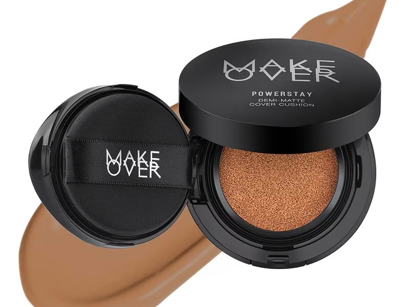Gambar compact Make Over Powerstay Demi-Matte Cover Cushion dengan kemasan hitam dan perak ramping dan terlihat profesional, menonjolkan perlindungan SPF dan coverage flawless-ny
