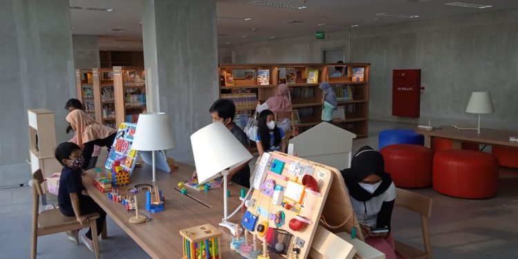 Gambar interior perpustakaan umum modern dengan orang-orang membaca.