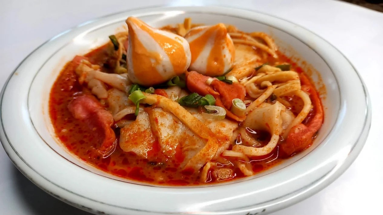 Semangkuk seblak dengan kuah merah menyala dan topping melimpah, menunjukkan tingkat kepedasan ekstrem.