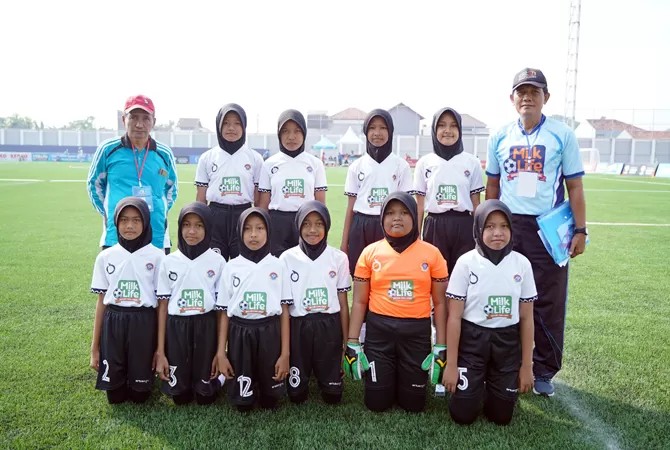 Gambar siswa-siswi berlatih sepak bola di lapangan hijau sekolah dengan seragam tim.