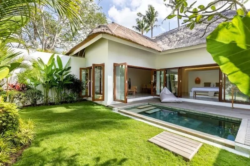 Interior villa minimalis modern dengan jendela besar menghadap pemandangan hijau yang menenangkan.