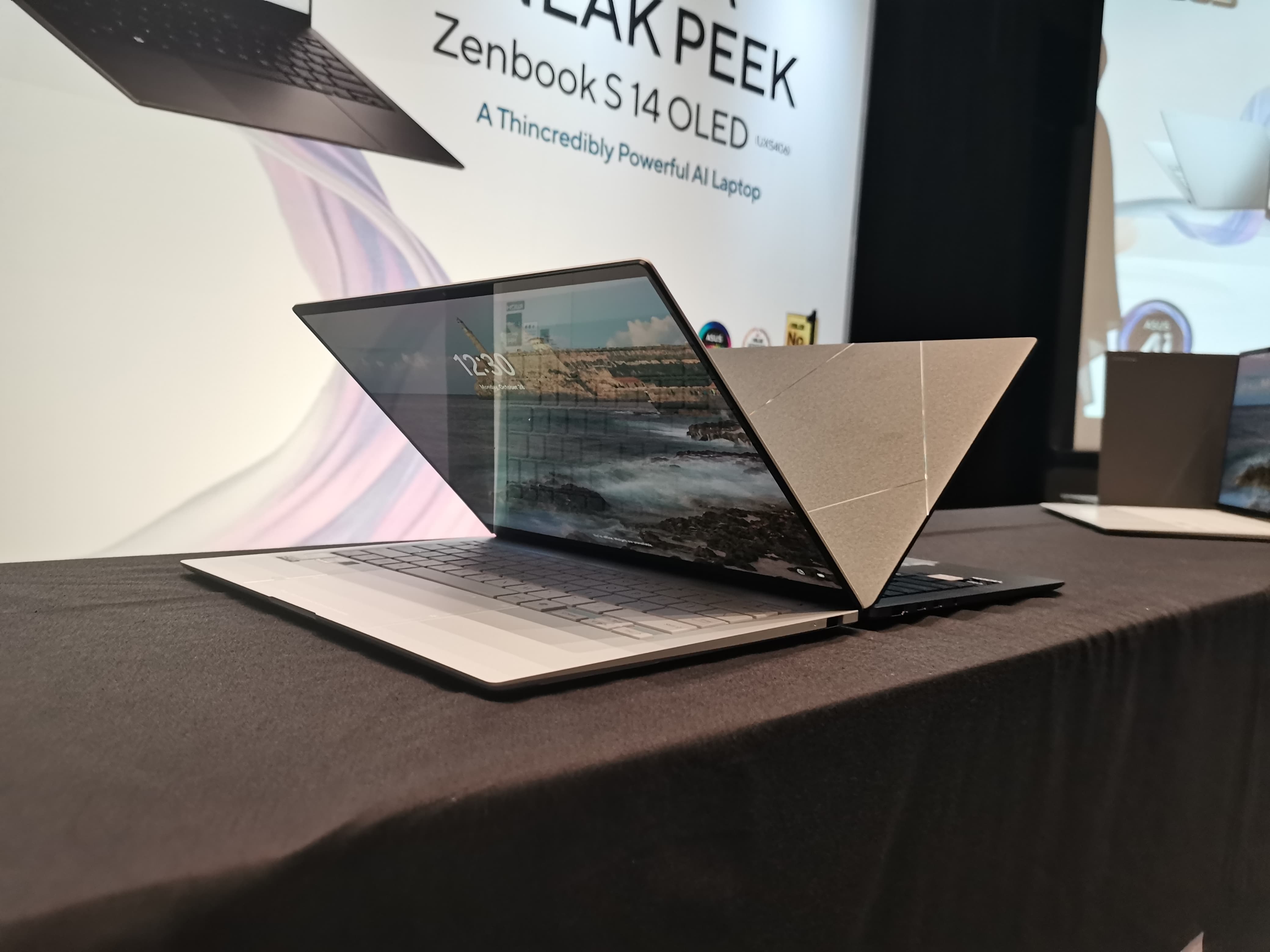 Gambar ASUS ZenBook 14 OLED diletakkan dengan elegan di meja kafe atau di ruang kerja bersama modern di Grand Indonesia, Jakarta Pusat, menonjolkan desain ramping dan portabilitasnya.