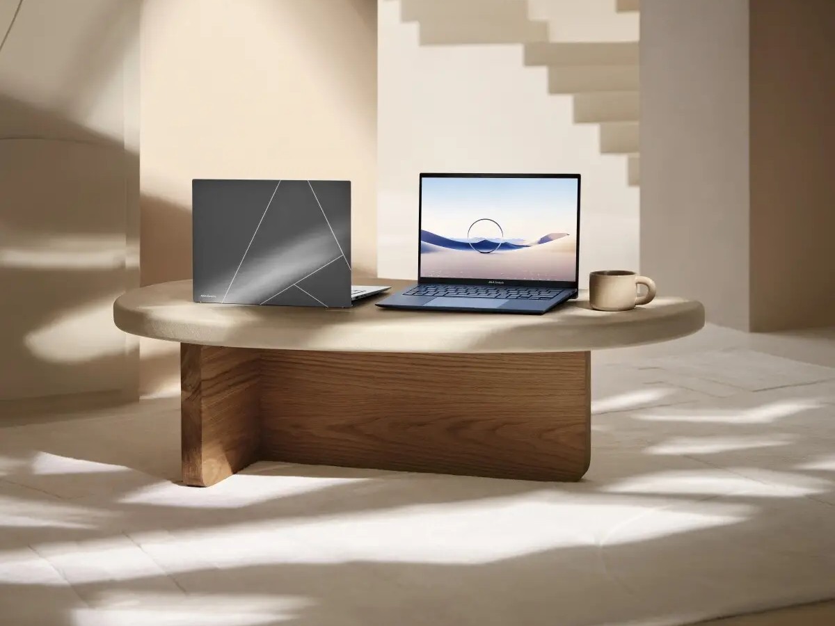 Gambar ASUS ZenBook 13 OLED/ZenBook S 13 OLED diletakkan dengan elegan di meja modern yang bersih, mungkin di kafe atau ruang kerja minimalis, dengan latar belakang samar Beachwalk Shopping Center Kut