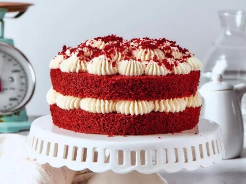 Sepotong kue red velvet dengan teh di meja cafe yang estetik.