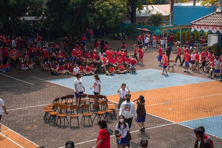 Gambar sekelompok siswa berinteraksi dengan warga komunitas dalam sebuah acara di luar sekolah.