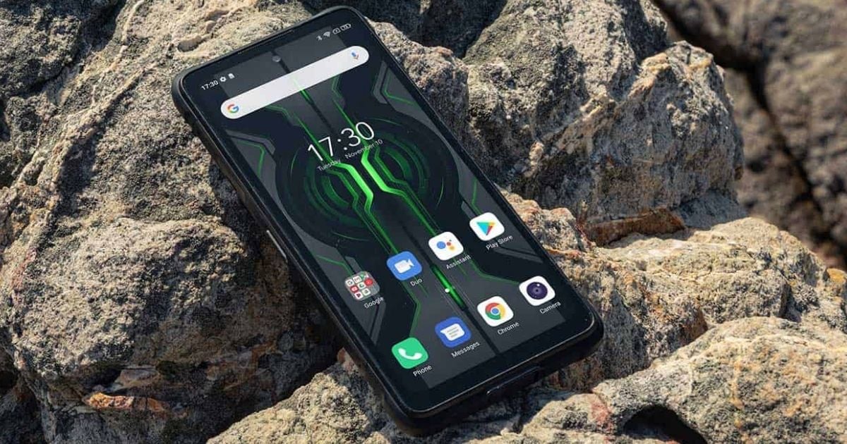 Ponsel rugged (tahan banting) yang terlihat terjatuh di genangan air atau lumpur namun tetap menyala.