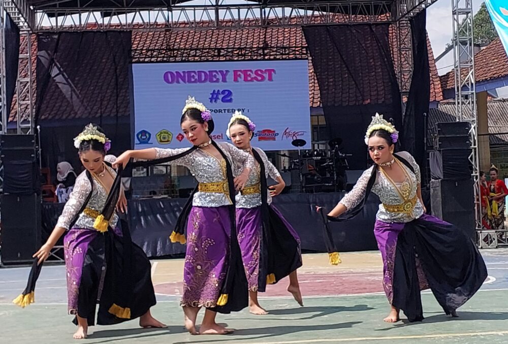 Gambar siswa-siswi mengenakan pakaian adat tradisional sedang menampilkan tarian daerah di panggung sekolah.