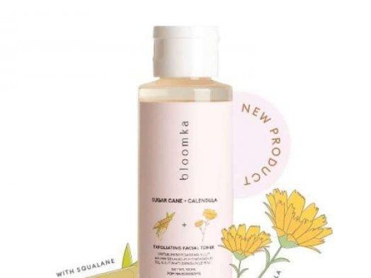 Gambar jar Bloomka Calendula + Probiotic Facial Moisturizer dengan estetika alami dan bersahaja, mungkin dengan elemen botani kecil atau pola mikroskopis samar, dengan latar belakang samar Bali.