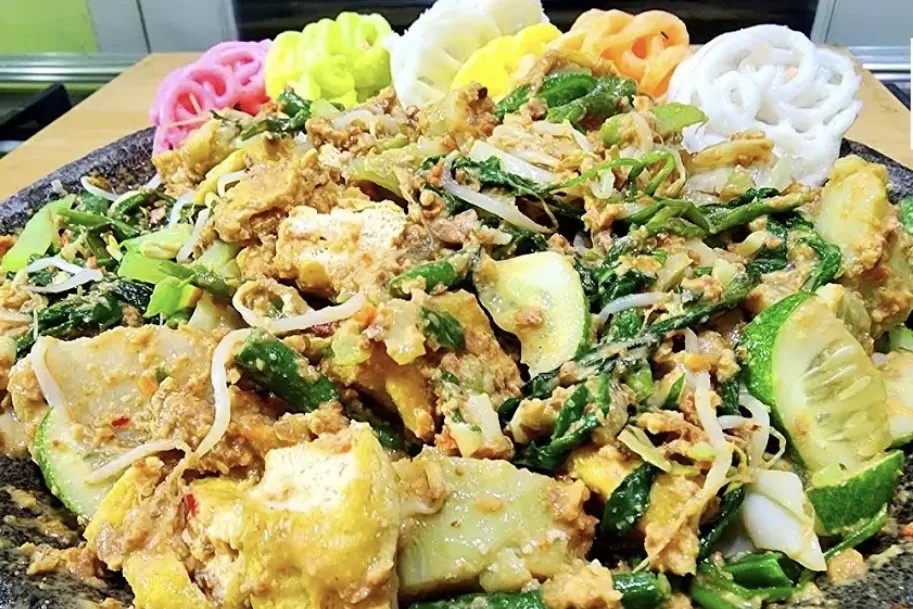 Sepiring lotek dengan aneka sayuran segar dan bumbu kacang melimpah disajikan di meja.